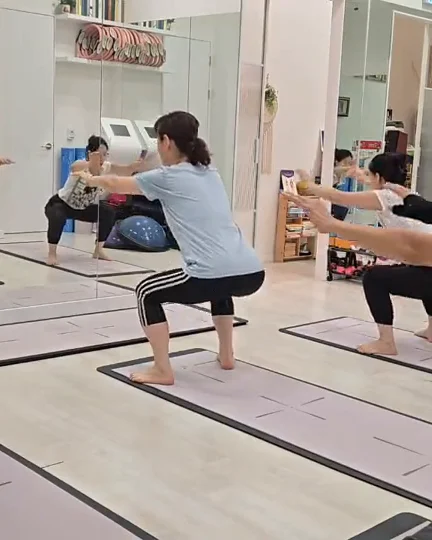 팔을 앞으로 뻗고 스쿼트하는 수업 장면